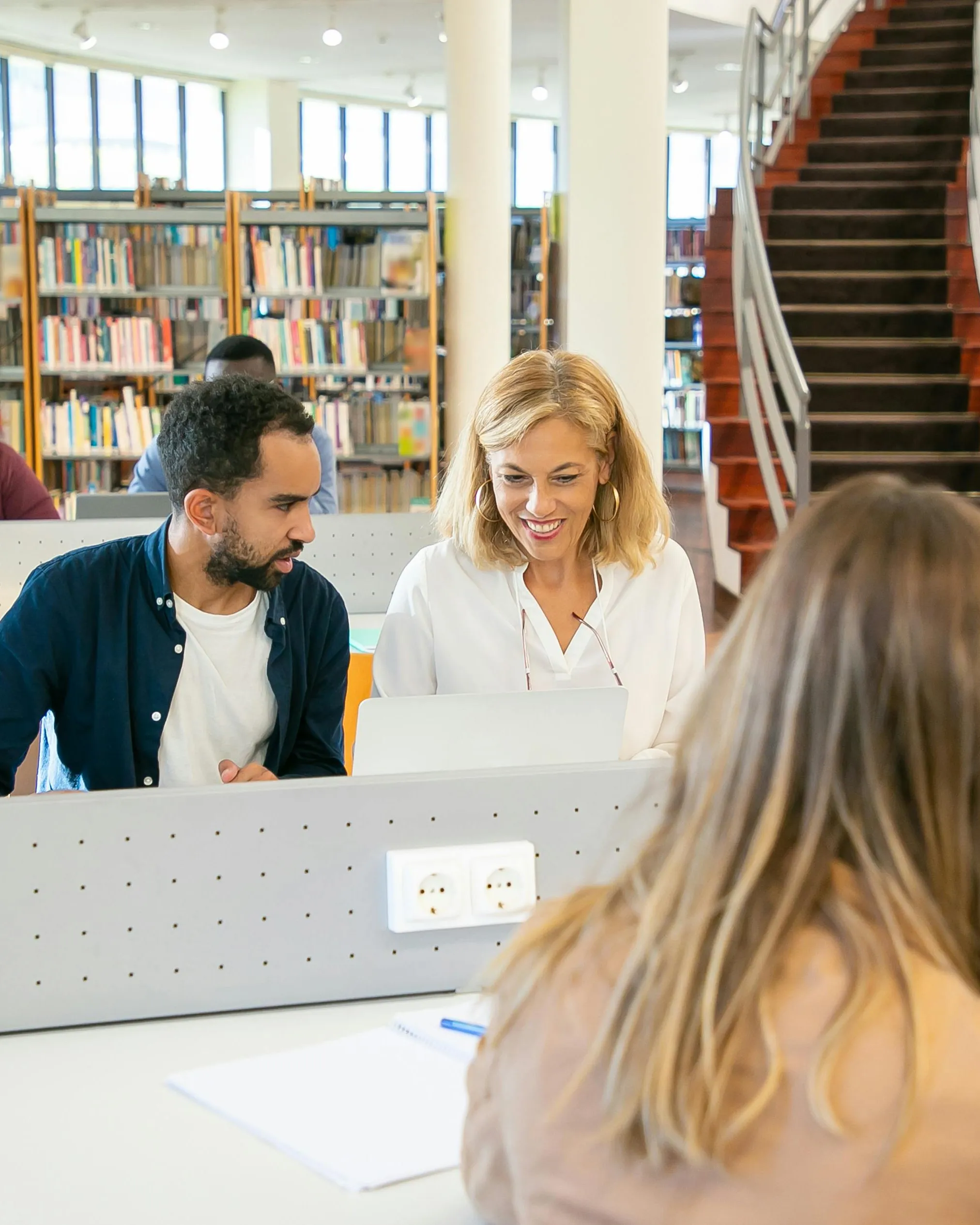 Persones aprenent a fer servir un ordinador en una biblioteca. Font: Pexels - Kampus Production