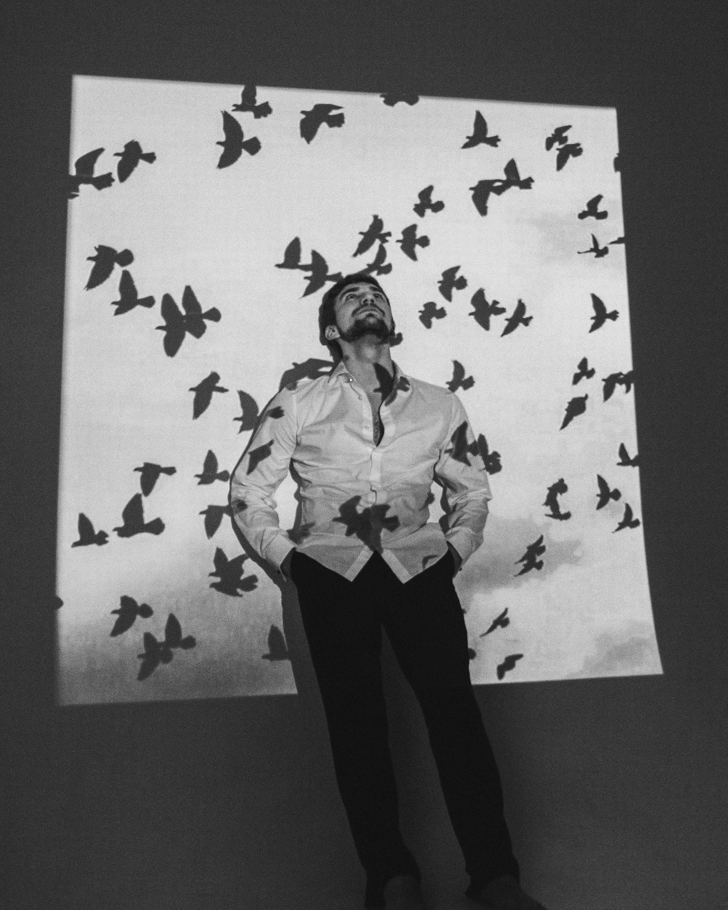 Foto de Olya Prutskova: https://www.pexels.com/ca-es/foto/home-recolzat-a-la-paret-amb-ombres-d-ocells-del-projector-7163732/