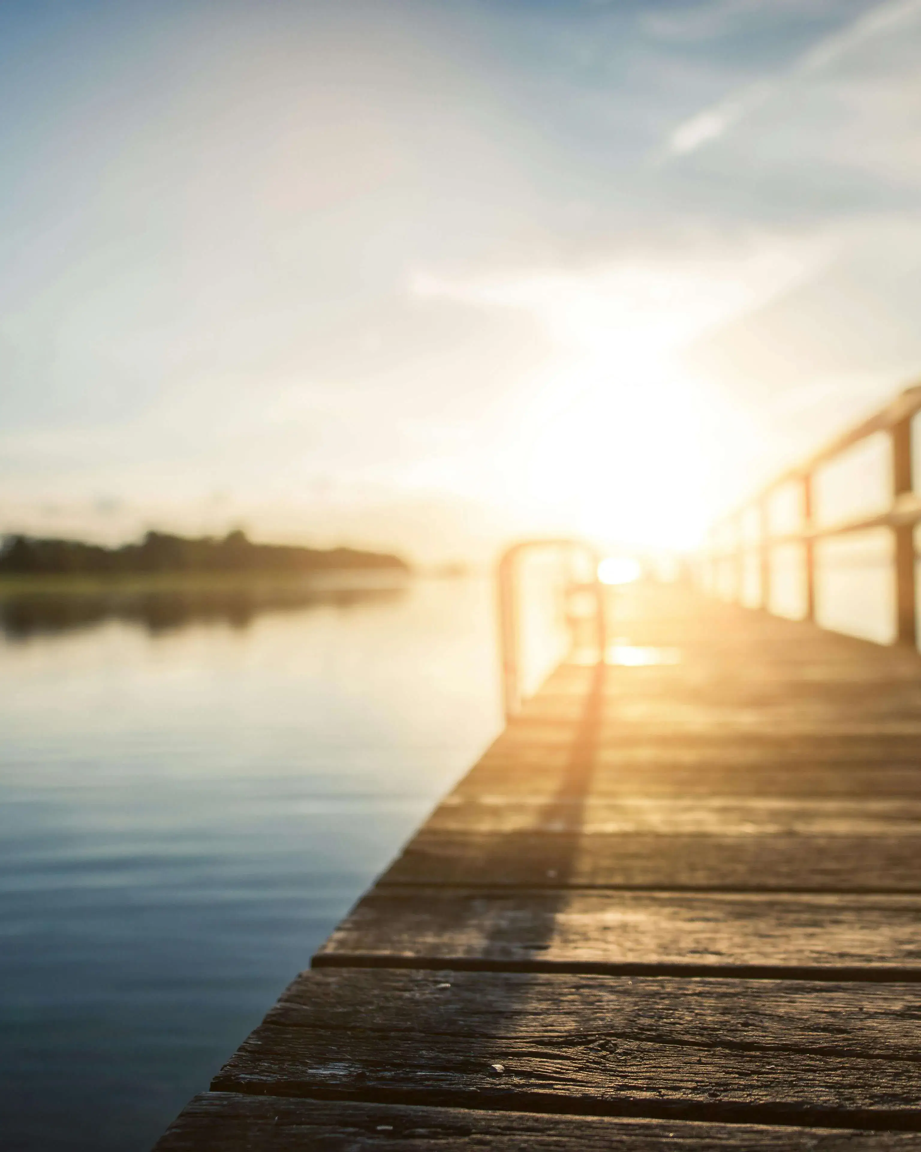 Llac amb passarel·la i posta de sol al fons