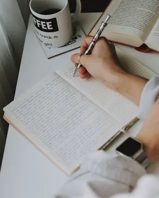Persona escrivint Persona en un escriptori escrivint a mà en una llibreta
