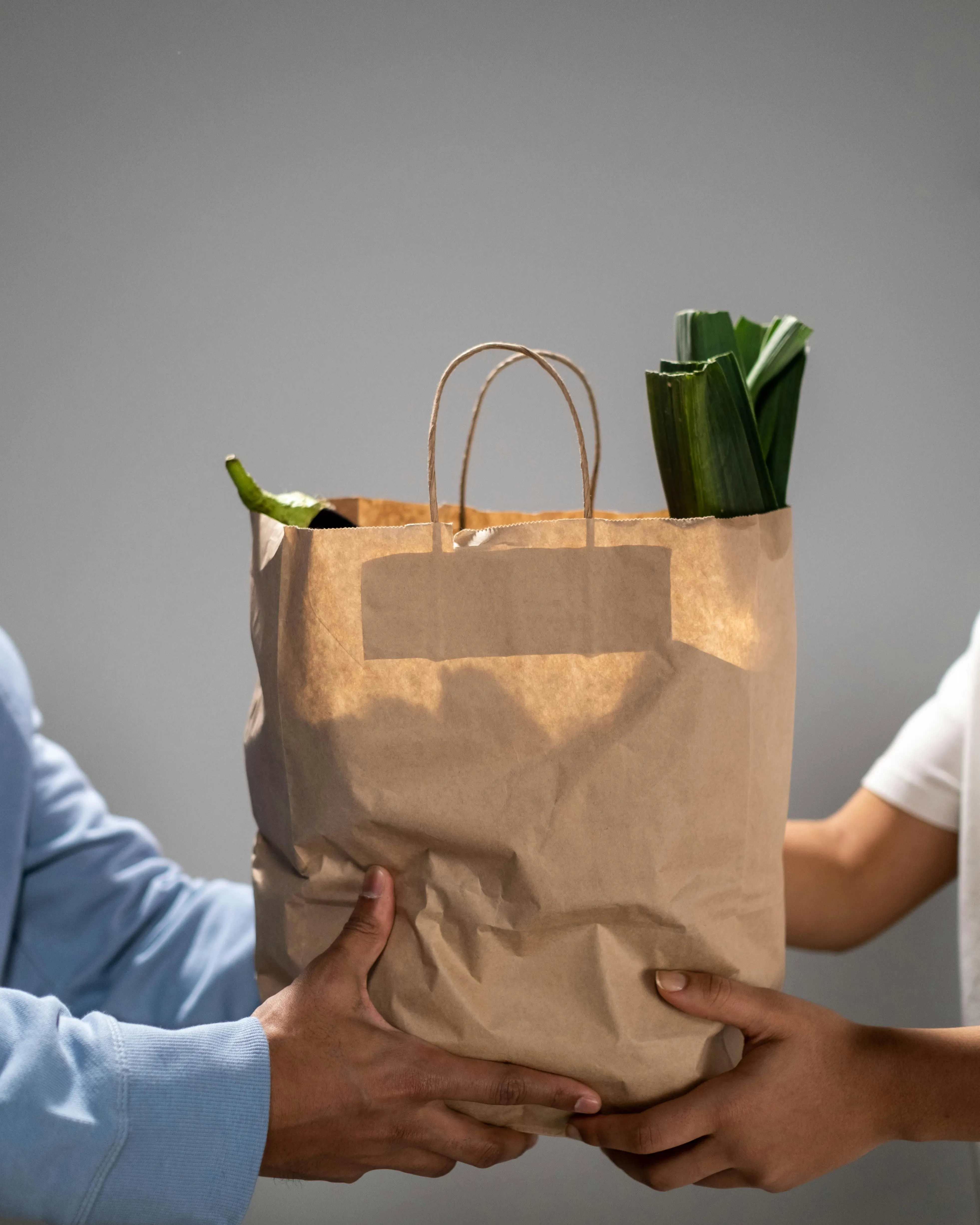 Mans agafant una bossa de paper amb compres a dins Mans agafant una bossa de paper amb compres a dins