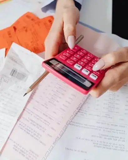 Persona amb documentació fent càlculs amb una calculadora