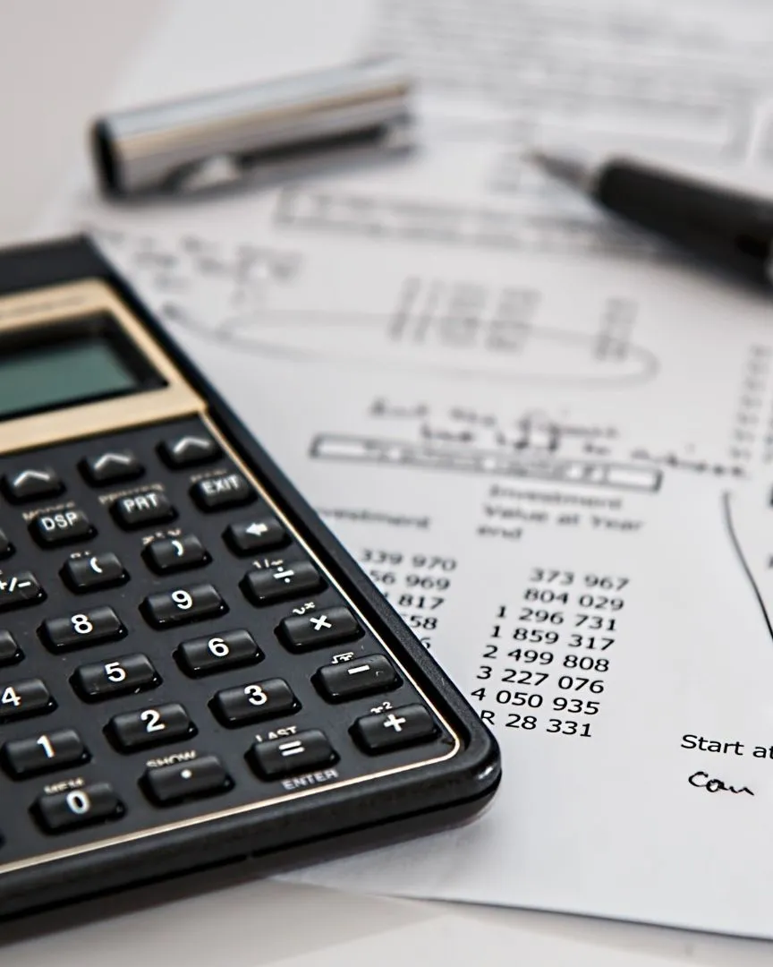 Calculadora sobre documents financers amb xifres i anotacions, al costat d’un bolígraf.