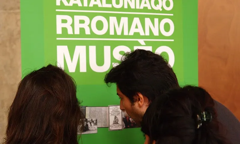 Persones mirant el cartell del Museu Virtual del Poble Gitano