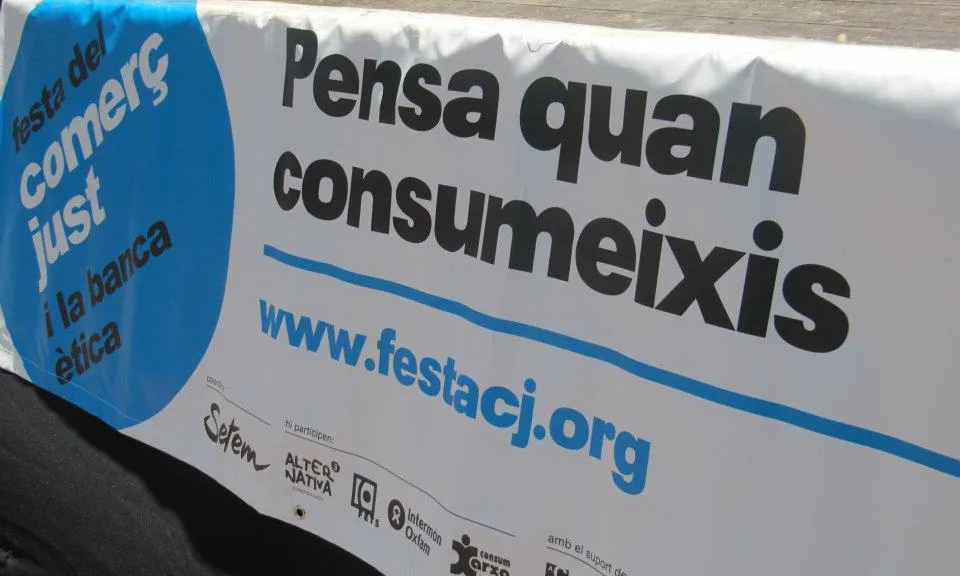 Pancarta de la Festa del Comerç Just: "Pensa quan consumeixis"