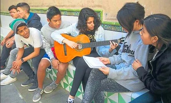 Nois i noies participants en el programa PSAU, una d'elles tocant la guitarra (Font: UB)