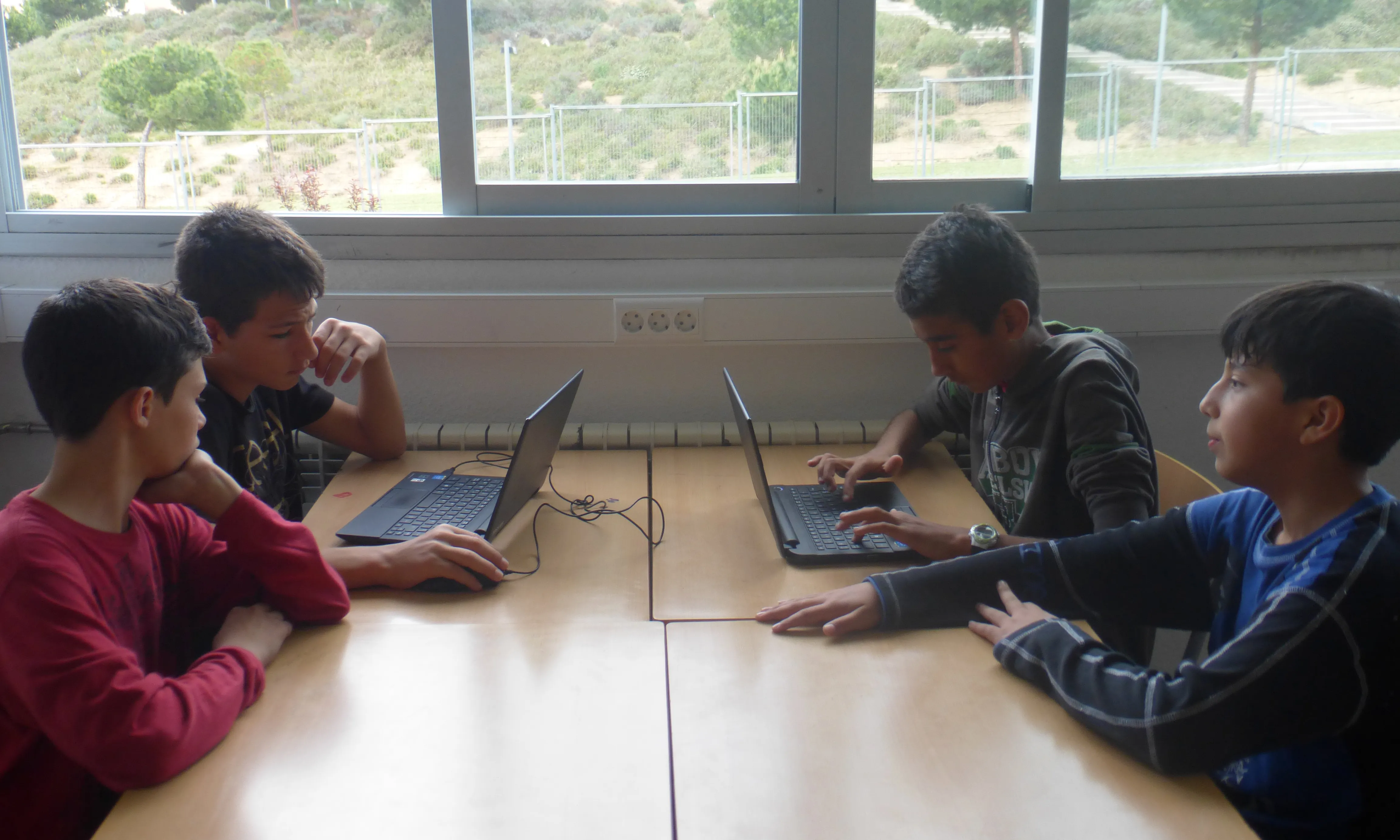 Grup de joves participants al programa UniX en una taula treballant amb ordinadors (Font: FAS)