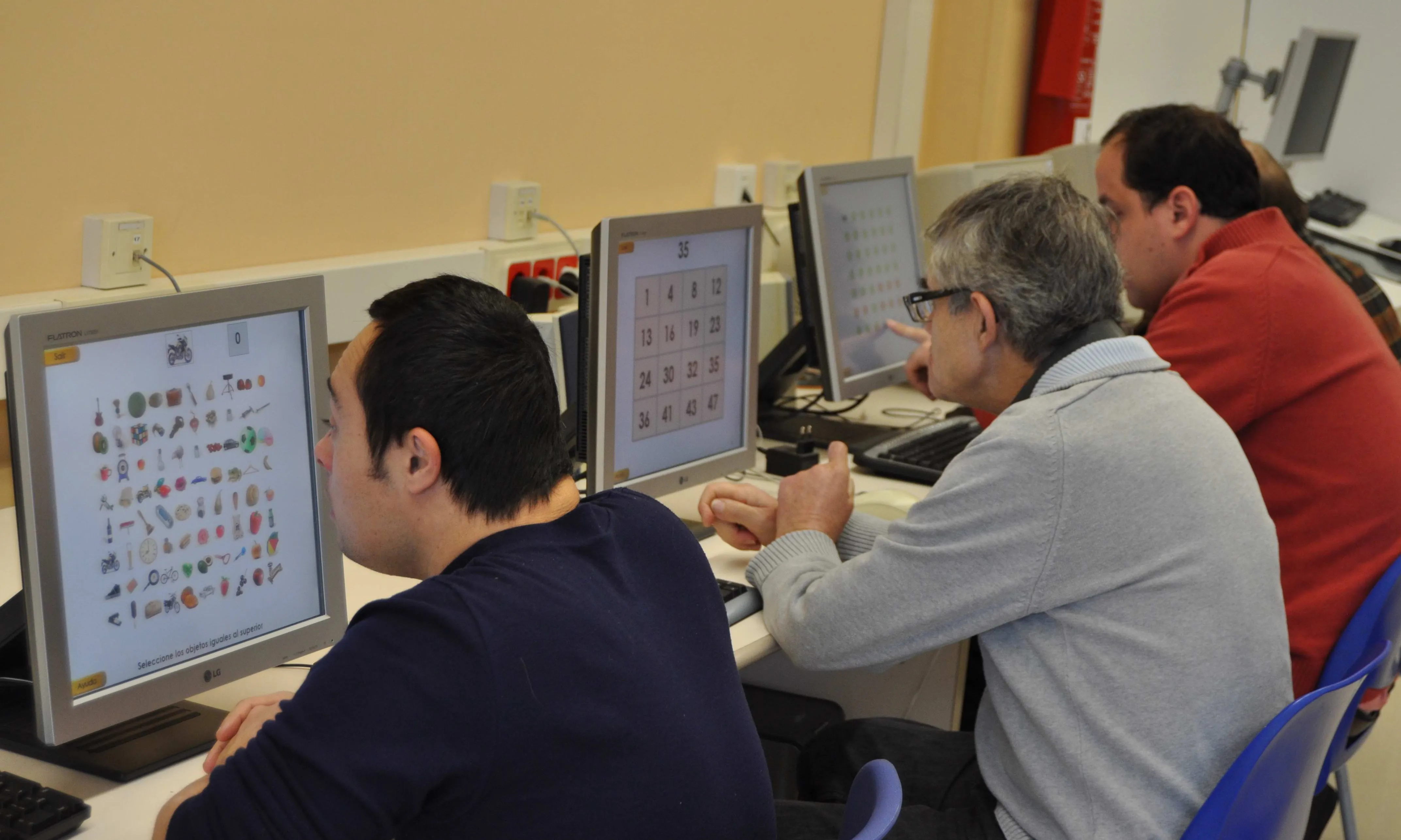 Homes beneficiaris dels programes d'Ampans treballant amb ordinadors (Font: AMPANS)