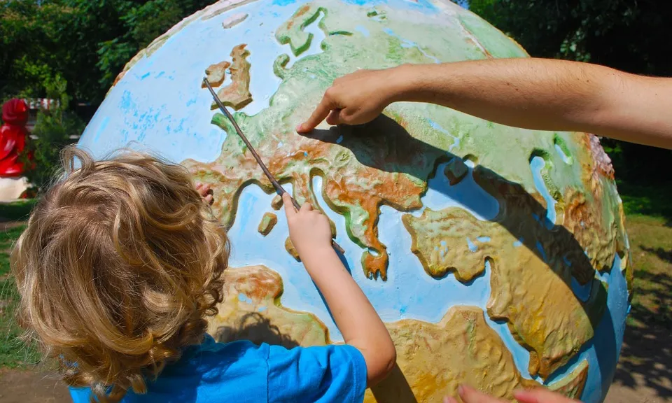 Educació en el lleure: Infant que experimenta amb la bola del món. Font: Pixabay