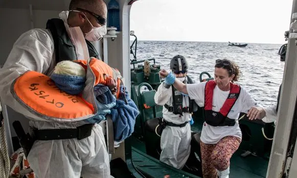 Astrid, llevadora de MSF entra en una embarcació de la Guàrdia Civil espanyola, amb un nadó acabat de néixer en una embarcació a la Mediterrània.( Font: Marta Soszynska / MSF)