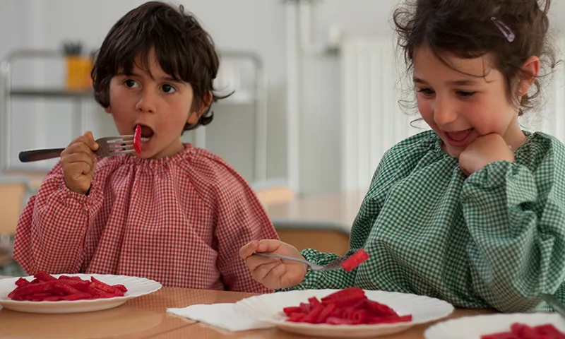 Infants menjant macarrons amb salsa de remolatxa - Menjadors escolars ecològics