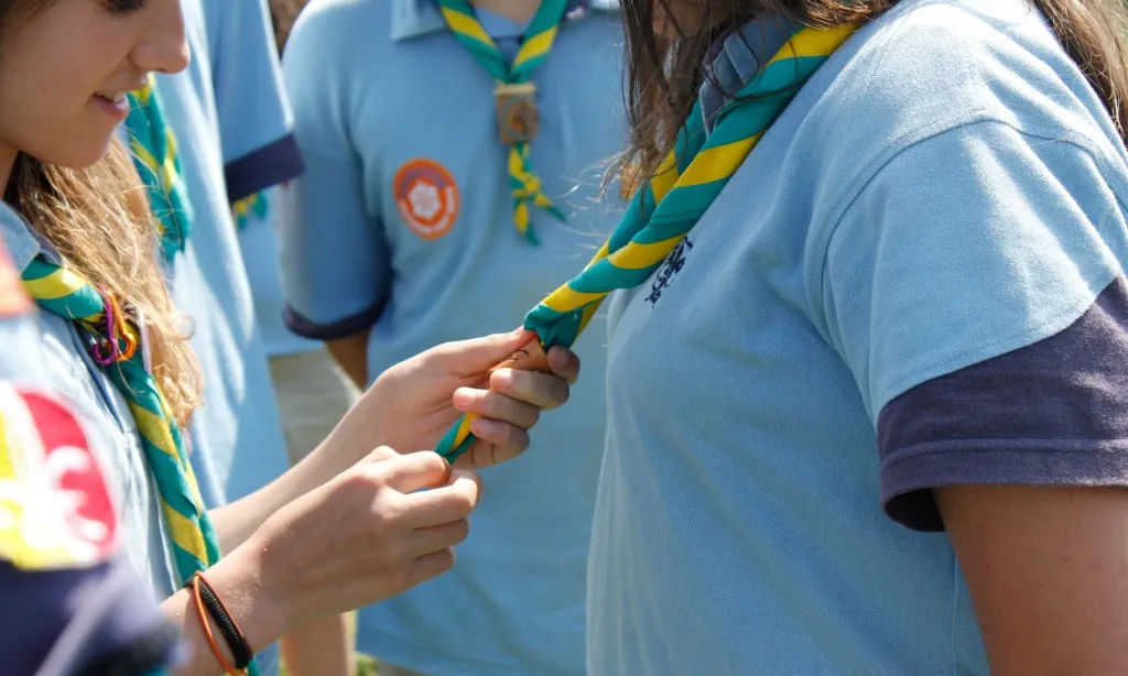 Joves lligant-se el fulard durant la promesa escolta