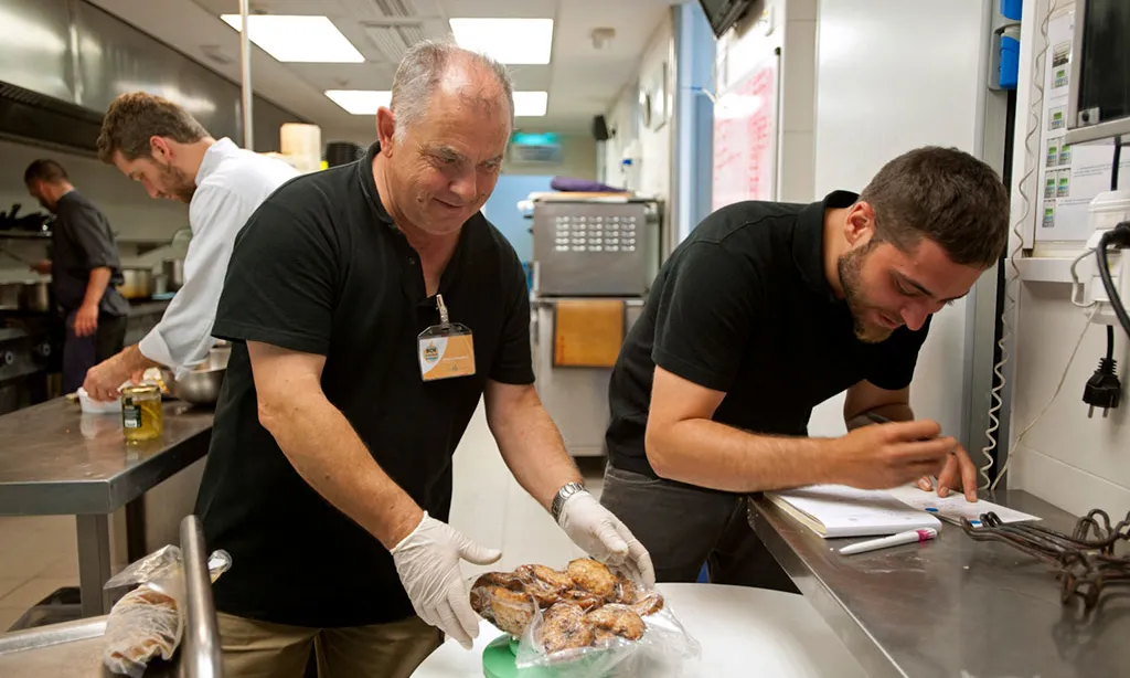 Membres de l'entitat recullen excedent de menjar en un establiment alimentari. 
