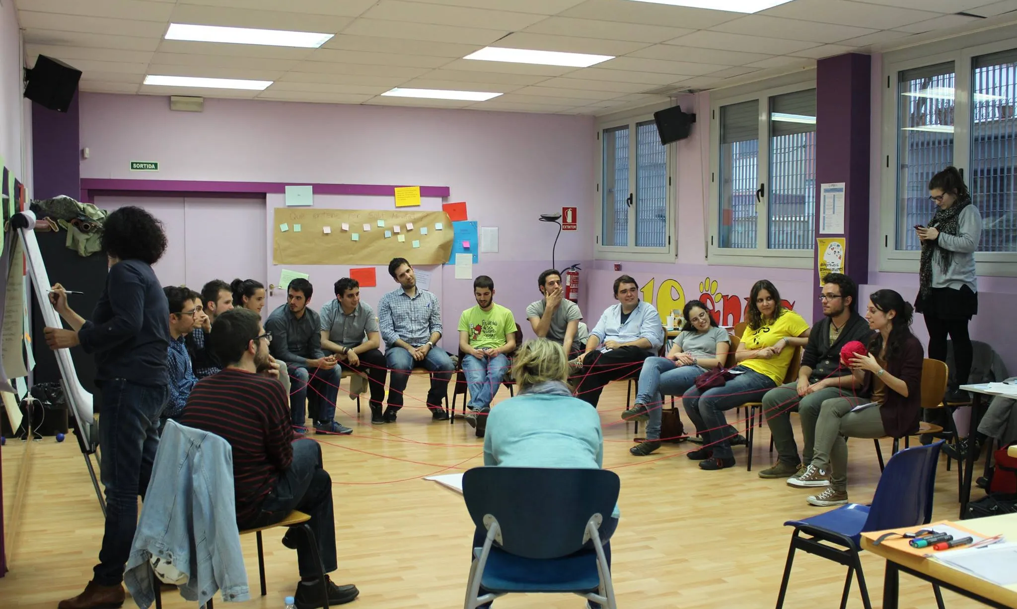 Un grup de joves "teixint xarxes" passant-se simbòlicament un cordill els uns als altres en una activitat de la 10a Àgora Jove.