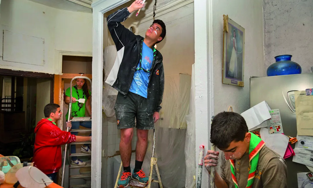 Un grup de joves escoltes fent tasques de rehabilitació d'un habitatge.