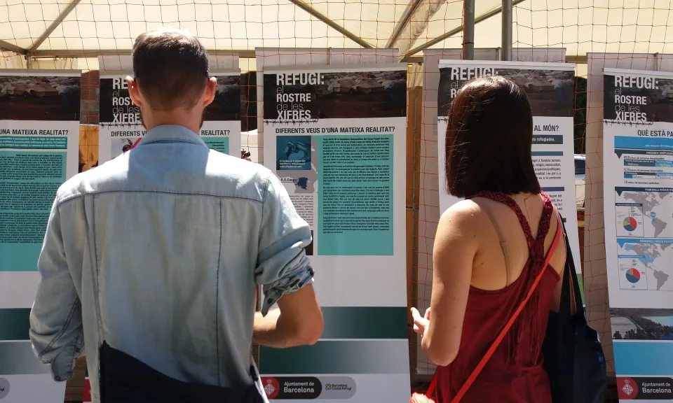 Dues persones presencien una exposició fotogràfica sobre persones refugiades. 