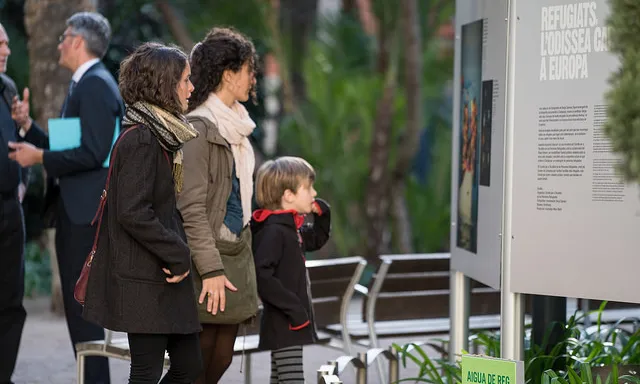 Una família mira una exposició sobre persones refugiades. 