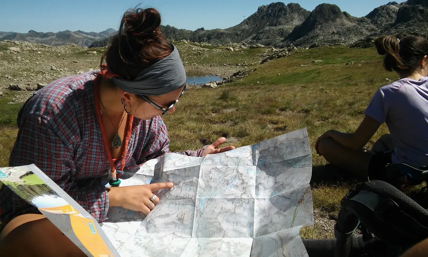 Una noia escolta mirant un mapa a l'Estany de Sant Maurici