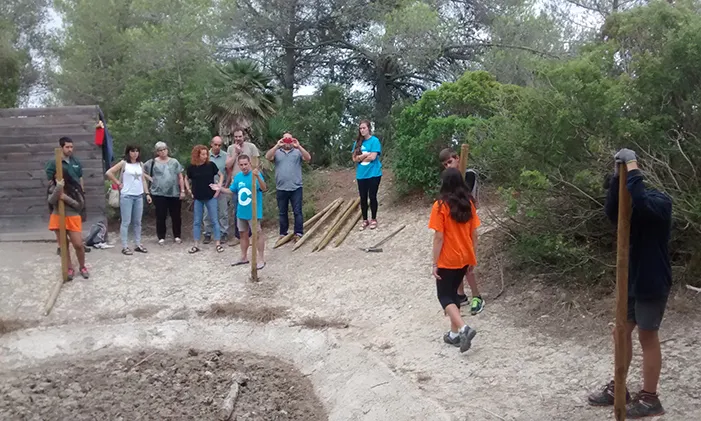 Joves fent un tancat amb pals de fusta