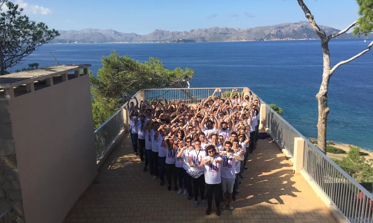 Persones fent perfomance amb la figura d'un triangle amb el mar de fons