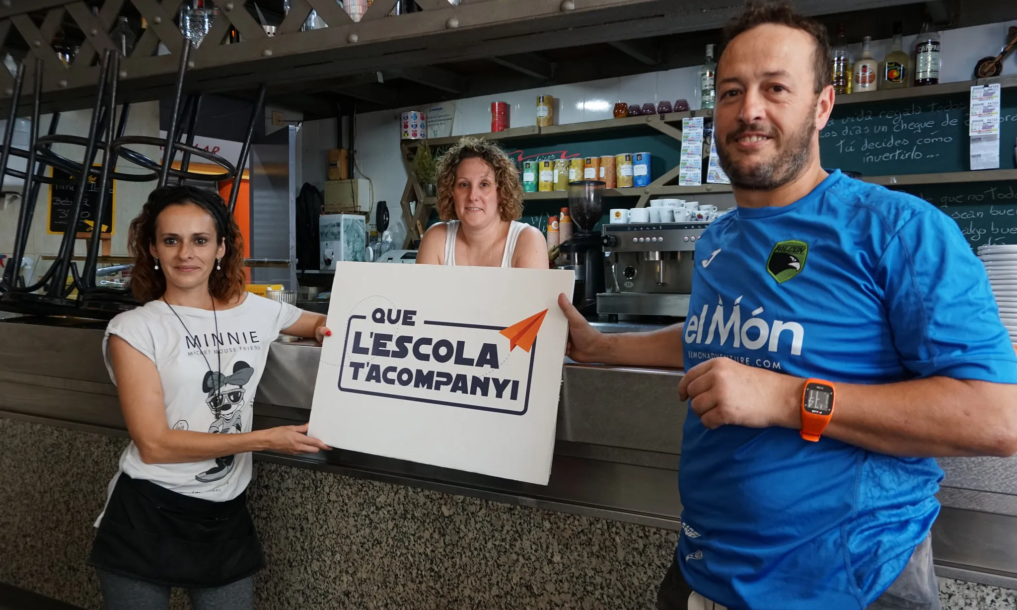 Persones ensenyant el cartell de la campanya ‘Que l’escola t’acompanyi’ 