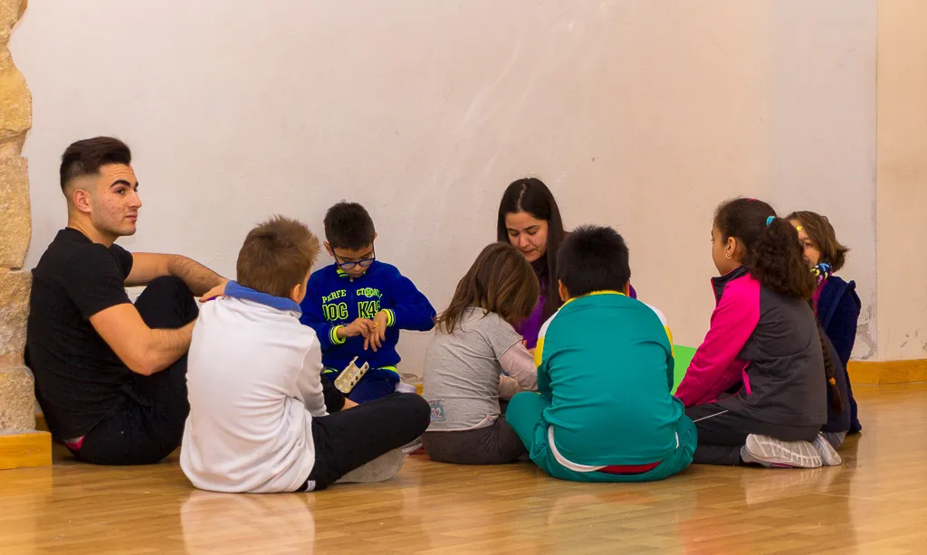 Monitors de lleure amb grup d'infants asseguts al terra