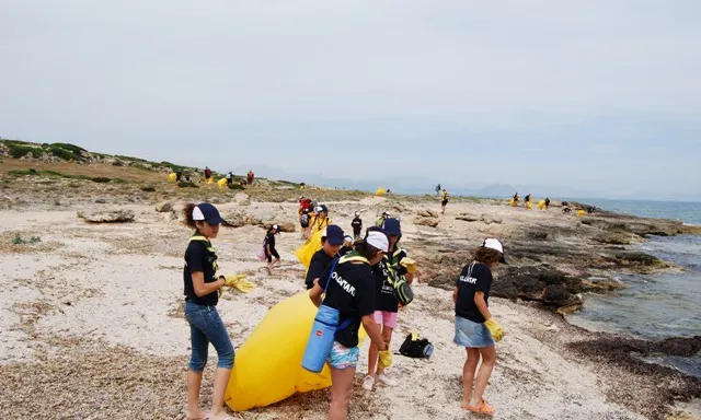 Un grup d'infants escoltes netejant un fragment de costa durant la campanya Clean up the Med
