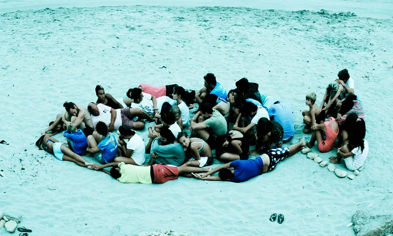 Persones a la platja fent la figura d'un peix
