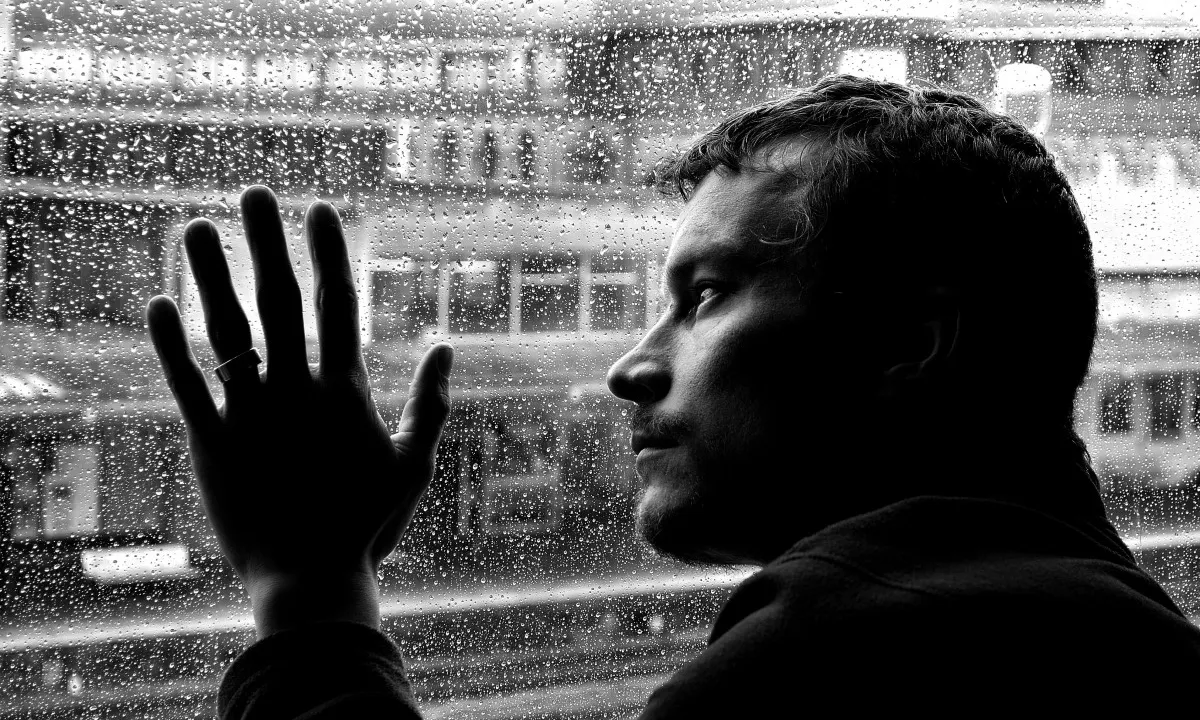 Un jove mira per la finestra en un dia plujós