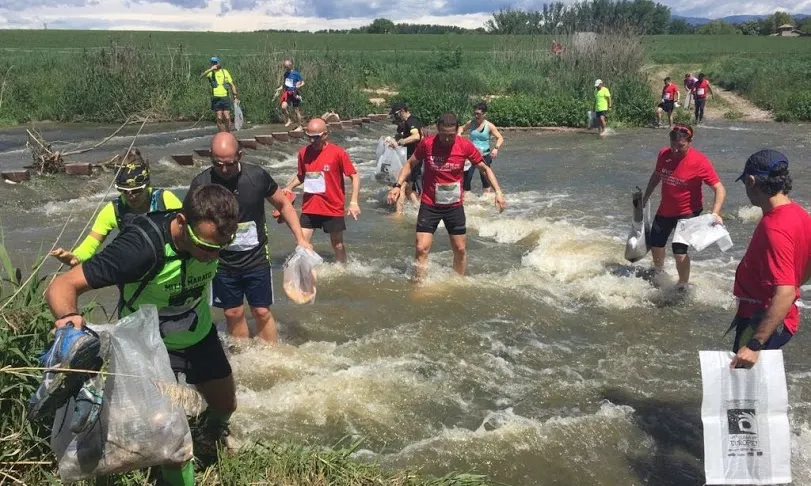Participants recollint deixalles en un riu