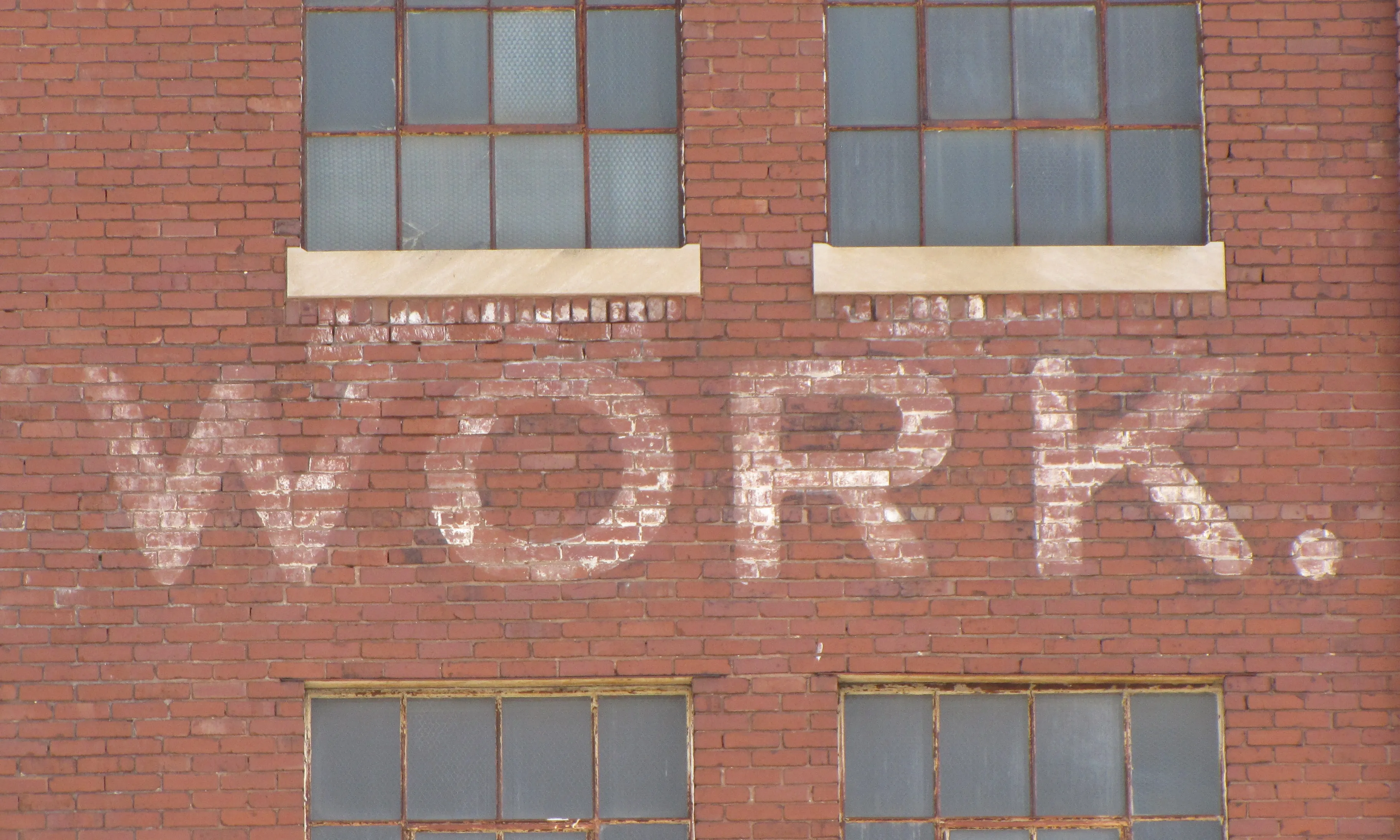 Work en blanc en una paret de totxos