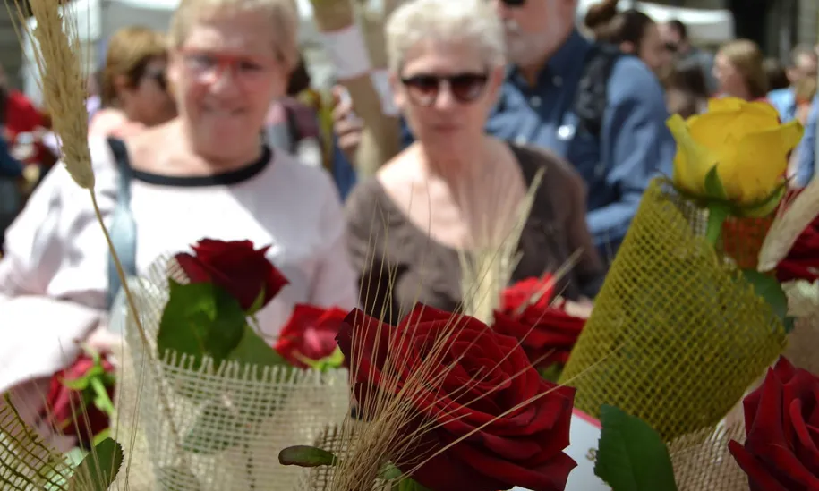 Dues dones que passegen per les Rambles s'aturen per mirar una rosa.