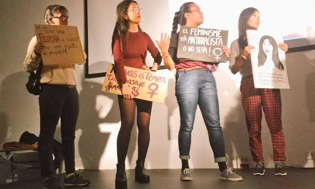 Noies a dalt d'un escenari amb cartells de protesta representant una obra de teatre