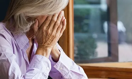 Senyora de cabells blancs tapant-se la cara amb les mans