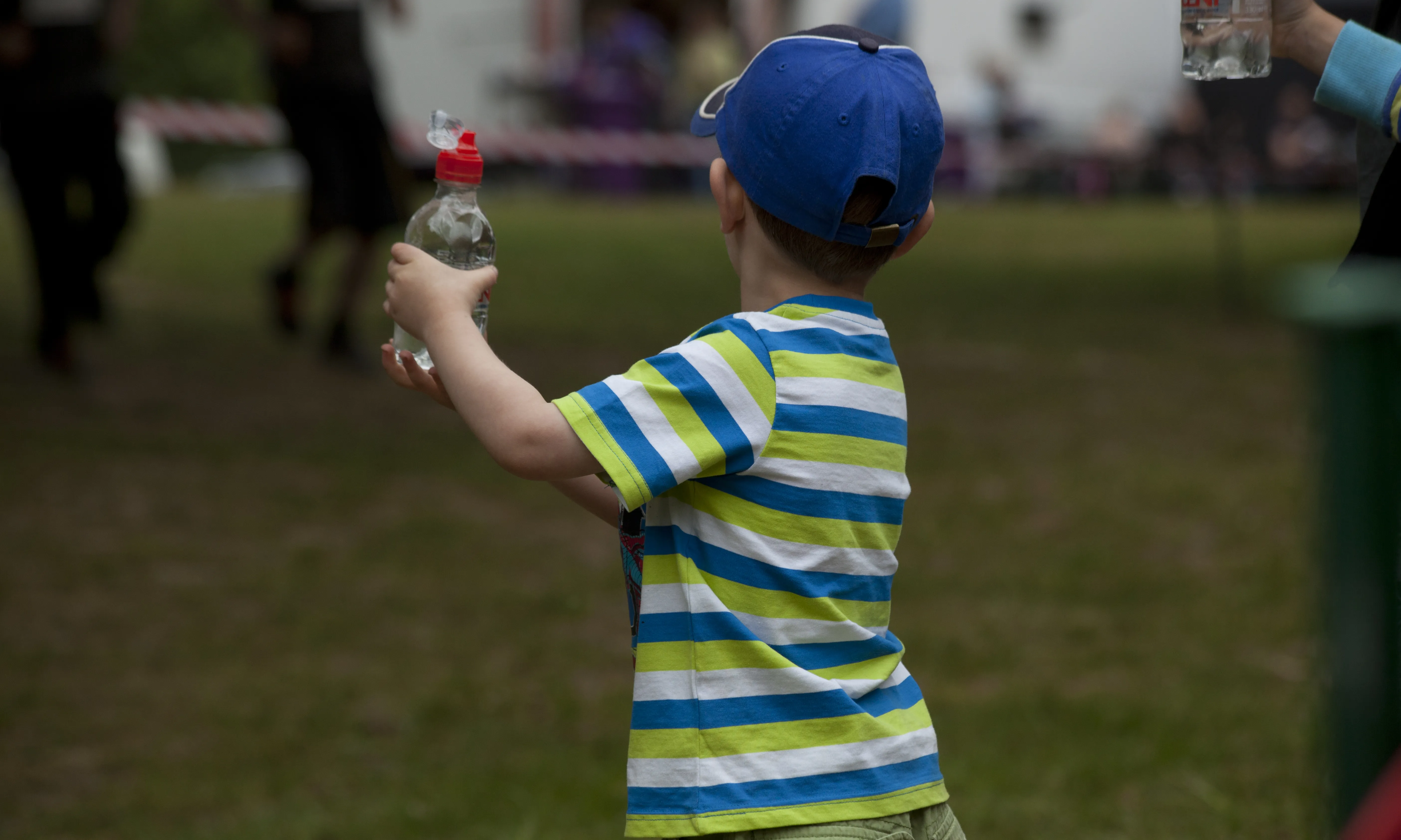 Nen de perfil amb una gorra al cap i una botella d'aigua a les mans