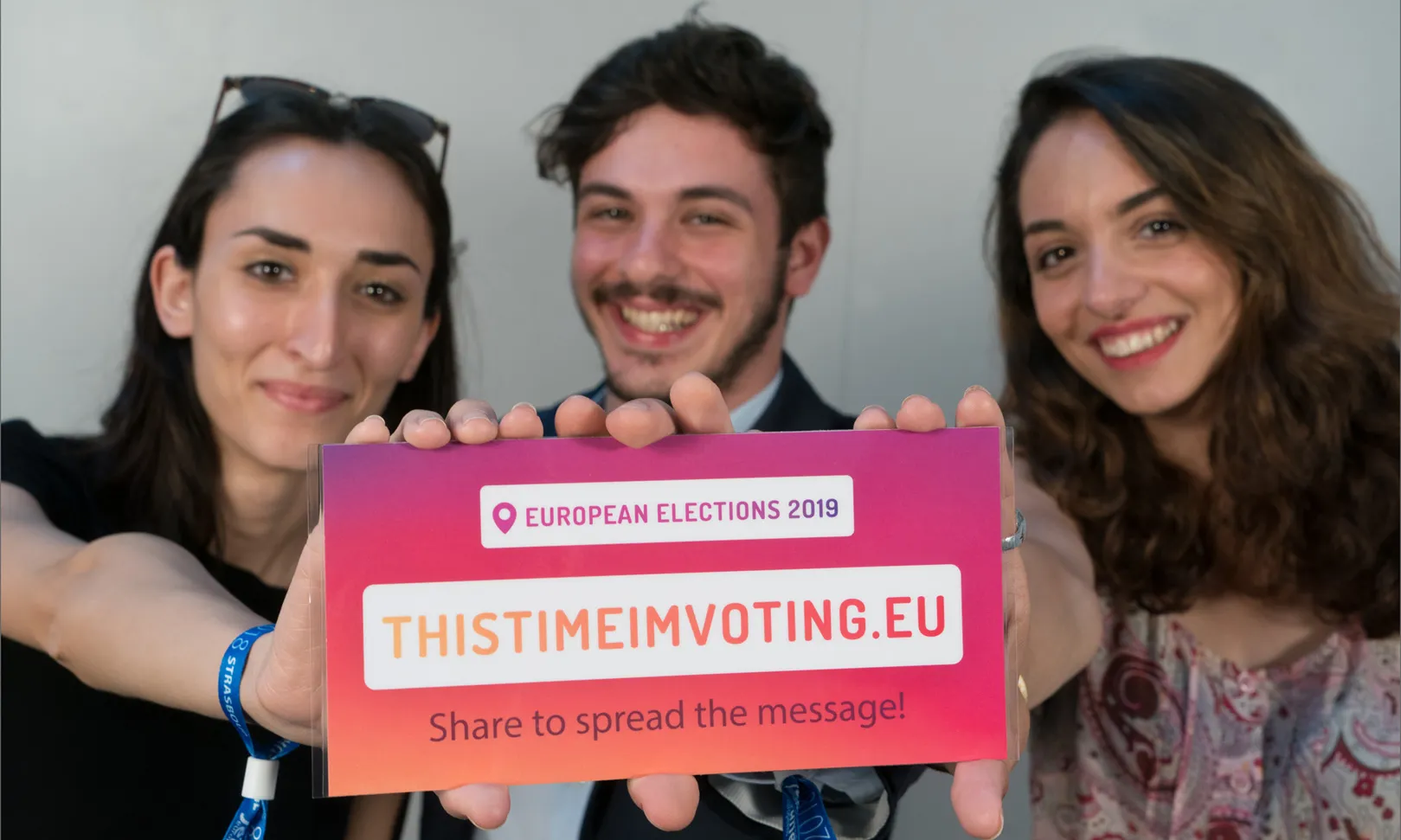 Tres joves mostren una targeta de la campanya