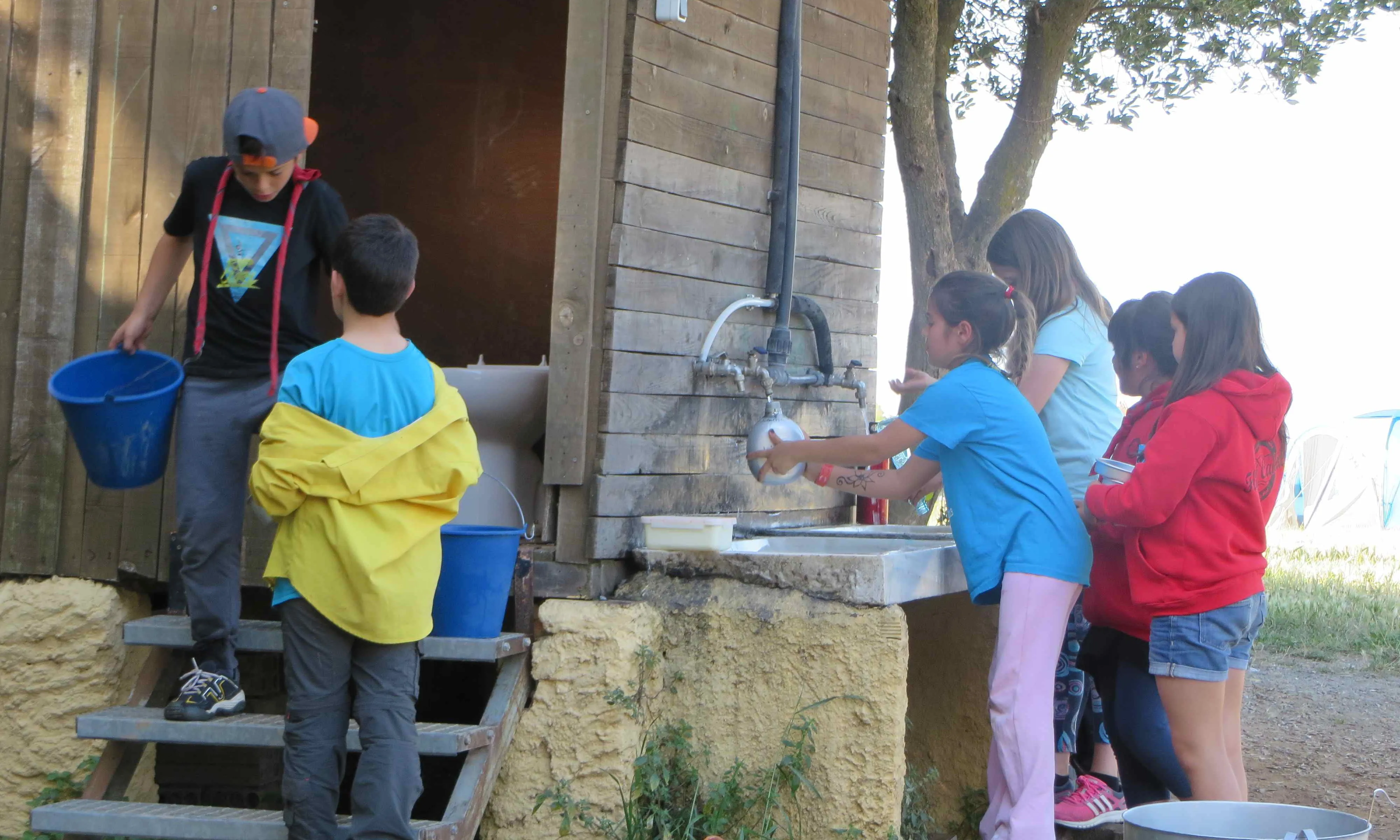 Un grup d'infants rentant plats i omplint cantimplores durant els campaments.
