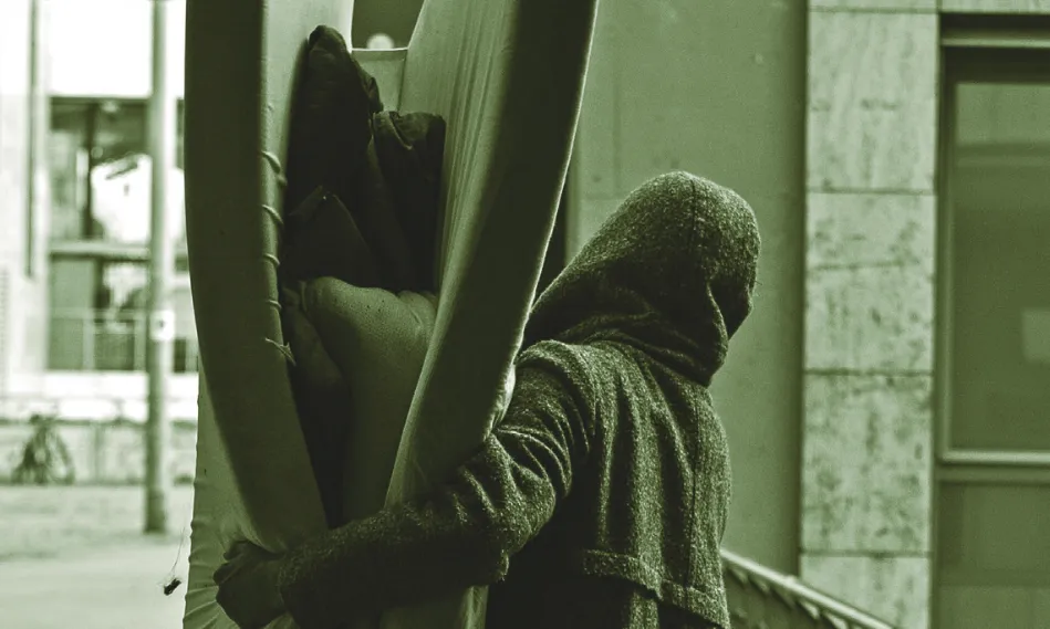 Una persona sense llar carrega un matalàs