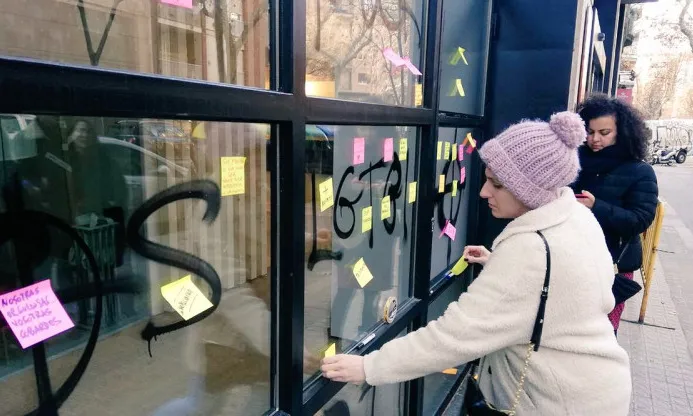 Dones posant 'post-its' en un vidre com a símbol de solidaritat amb les víctimes
