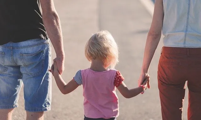 Una família camina, agafant de la mà a la seva filla.