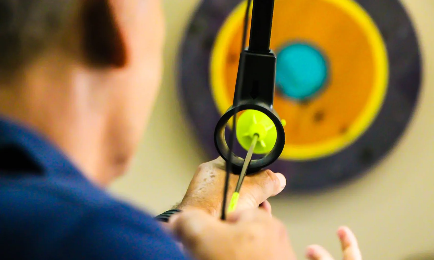 Home apuntant a una diana amb fletxa