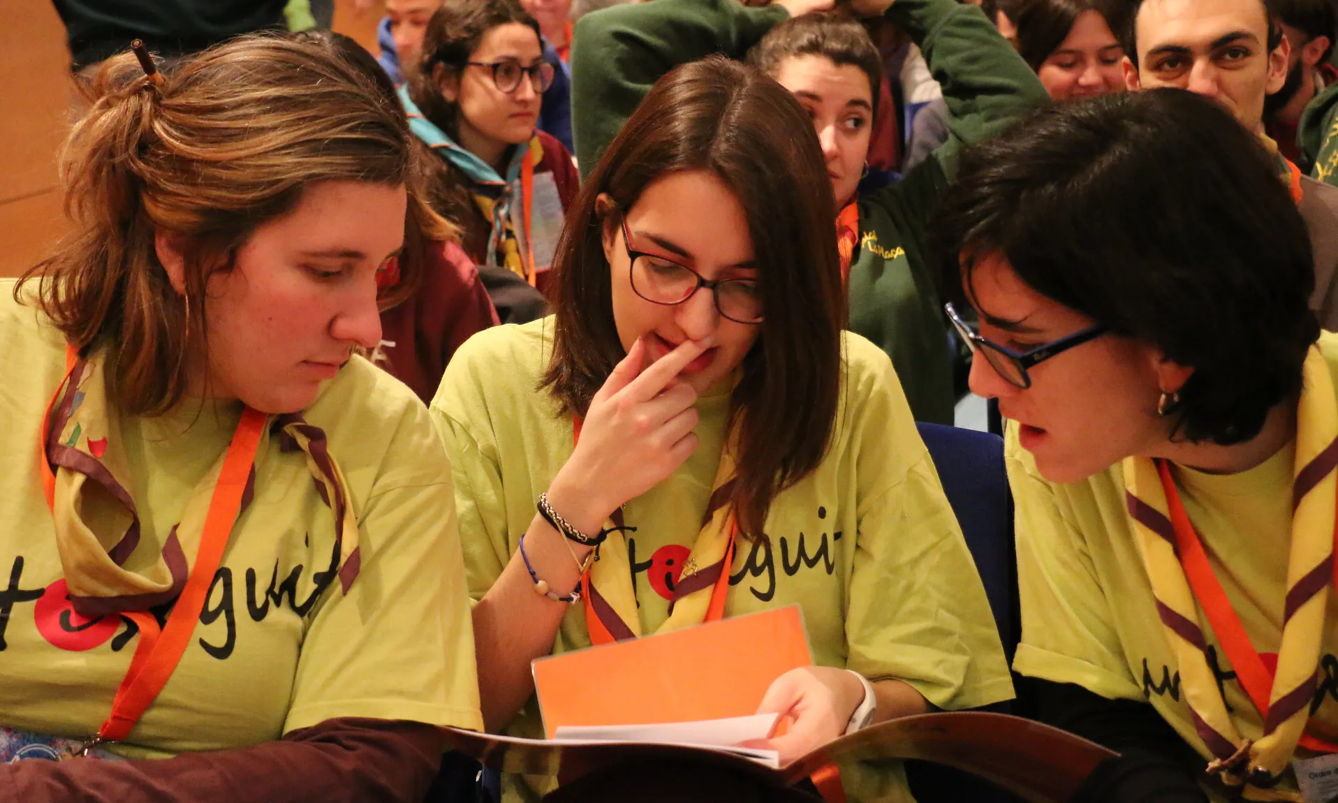 Tres noies assegudes mirant el mateix paper