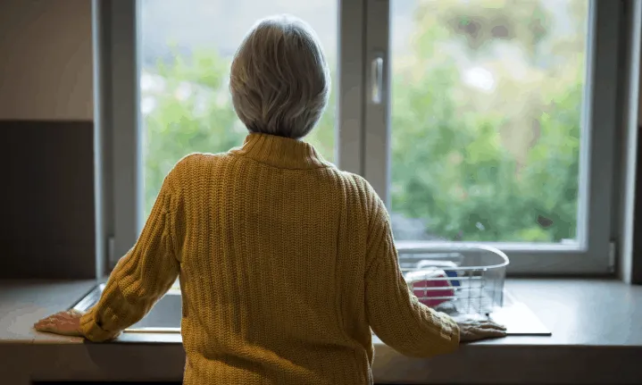 Una persona gran amb Alzheimer observa per la finestra.