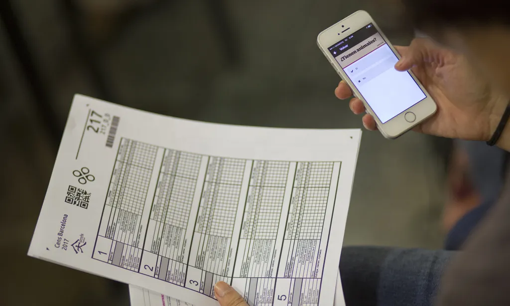 Persona amb mòbil en una mà i paper en una altra