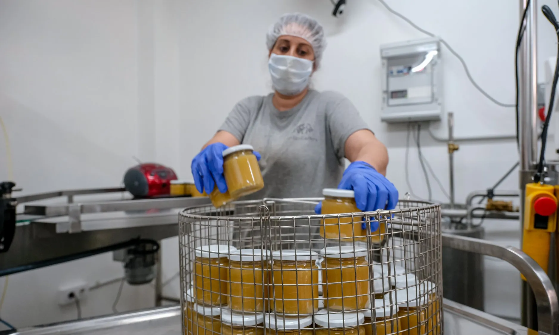 Una dona amb mascareta organitzant pots de vidre amb menjar