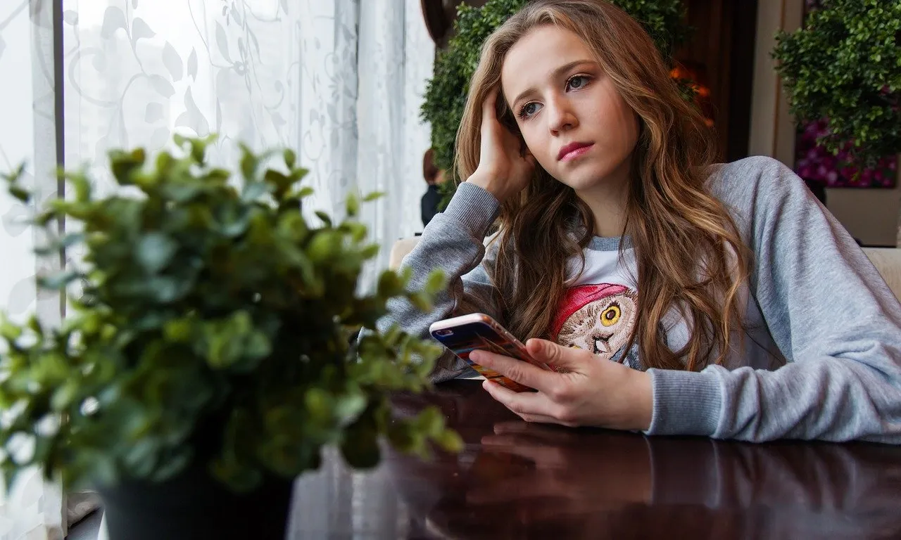 Una noia amb el telèfon a la mà i la mirada perduda