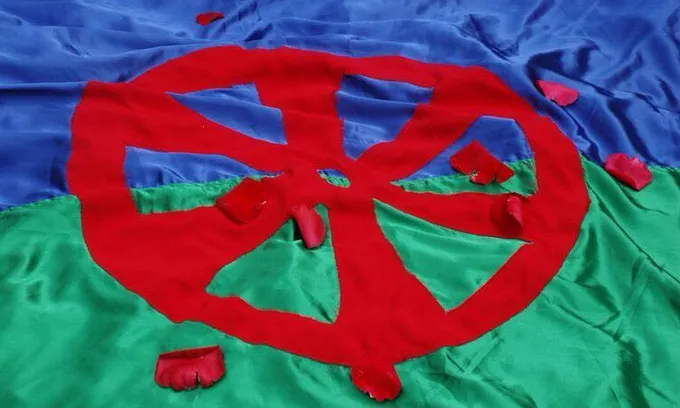 Bandera del Poble Gitano amb pètals vermells a sobre