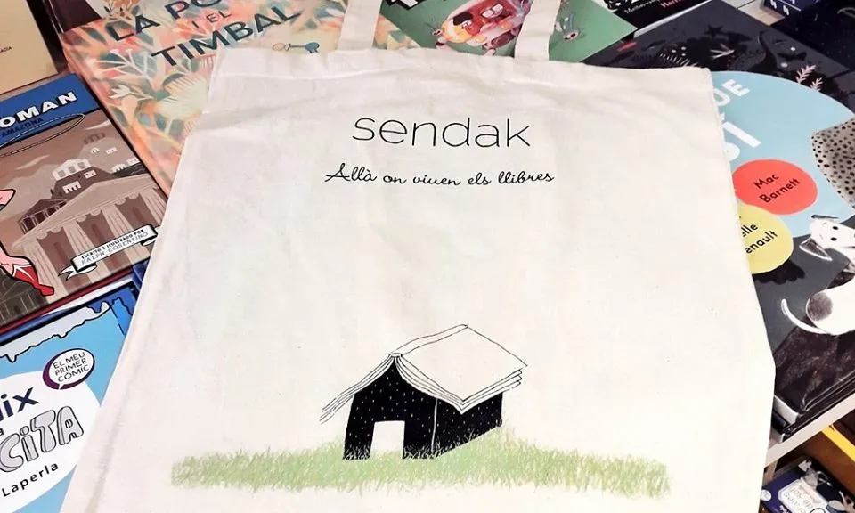 Tote bag a sobre de llibres, amb la frase escrita: Sendak. Allà on viuen els llibres