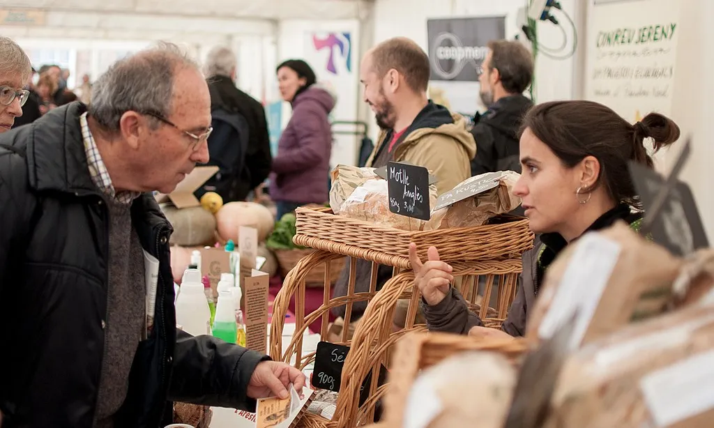 Fotografia de dos persones participant a la Fira d'Economia Solidària de Catalunya. Imatge de Xarxa d'Economia Solidària. Lllicència d'ús CC BY-SA 4.0