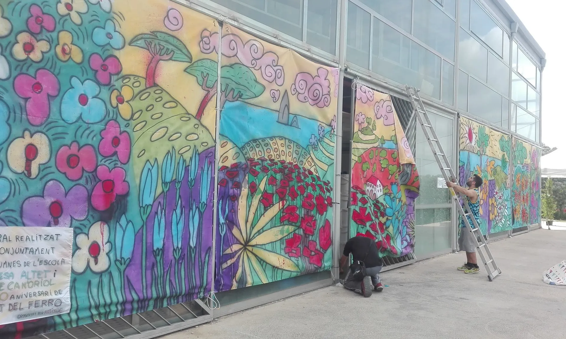 Dues persones muntant un mural